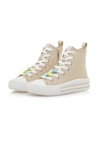 Zapatillas altas beige con cordones blancos, una puntera de goma y cuentas decorativas multicolores. Presentan una cremallera lateral y una suela a rayas.