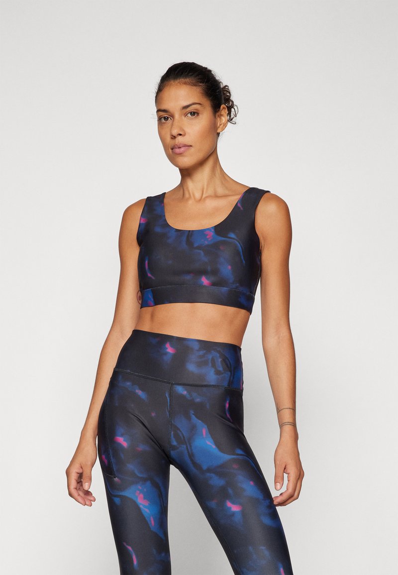 Svart og blå atletisk crop top og høye leggings med et flytende mønster med rosa aksenter; laget av et elastisk, fukttransporterende stoff.