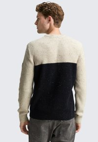 Gestrickter Pullover in Creme und Marineblau mit einem horizontalen Farbblockdesign, geribbelter Textur und gesprenkelten Akzenten. Klassischer Rundhalsausschnitt.