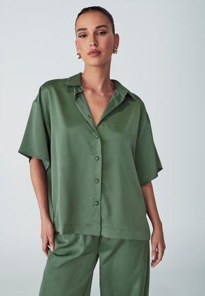 Satiinista vihreä nappipaita kauluksella, lyhyillä hihoilla ja rentolla leikkauksella. Sileä pinta ja yksinkertainen muotoilu, yhdistettynä yhteensopiviin housuihin.
