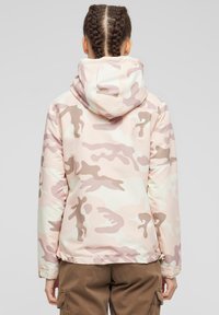 Rožinė kamufliažinė striukė su kapišonu, pagaminta iš lygaus, lengvo audinio. Turi laisvo prigludimo siluetą ir elastingus rankogalius.