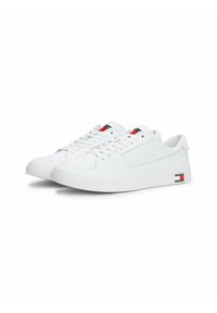 Białe skórzane sneakersy z gumową podeszwą, charakteryzujące się teksturowaną powierzchnią, perforacjami oraz akcentem logo w kolorach czerwonym, białym i niebieskim.