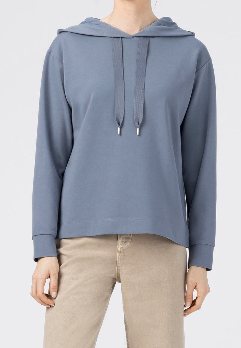 Ljusblå hoodie tillverkad av mjukt tyg, med dragsko i huvan, långa ärmar och en avslappnad passform. Slät struktur med minimala detaljer.