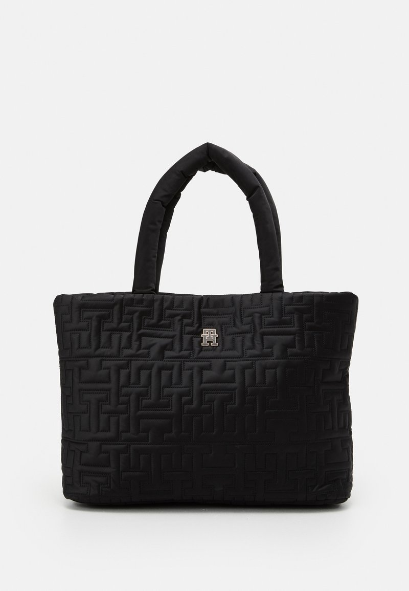 Sac cabas noir matelassé avec poignées rembourrées et motif géométrique en relief, arborant un petit logo métallique au centre avant.