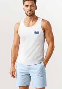 White tank top with blue "NEVER LESS" text, paired with light blue shorts. Features a round neckline and casual fit. Smooth texture.