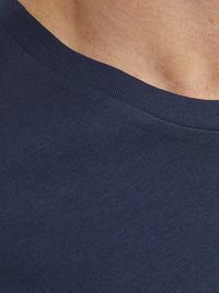 Marineblå bomulds T-shirt med en glat tekstur og ribbet rund hals. Billedet viser en tæt på af stoffet, hvor den bløde fornemmelse og farven fremhæves.