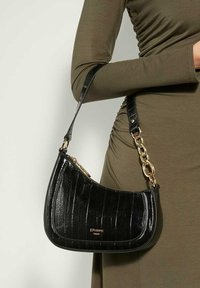Black patent leather shoulder bag with a curved shape, gold chain accents, and a zip closure, featuring a crocodile texture.