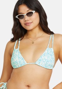 Lys blå bikini topp med blomstermønster, trekantede kopper, tynne stropper og justerbare bånd. Glatt tekstur og minimal maskinvare.
