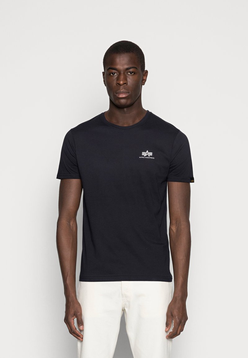 Navyblaues T-Shirt mit kurzen Ärmeln aus Baumwolle, mit einem kleinen weißen Logo auf der linken Brust und einem Etikettenakzent am Ärmel.