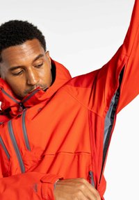 Rote wasserdichte Jacke mit Kapuze, ausgestattet mit grauen Reißverschlüssen und mehreren Taschen. Glatte Textur und taillierte Passform, ideal für den Einsatz im Freien.