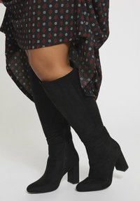 Czarne zamszowe botki do kolan z masywnym kwadratowym obcasem i dopasowanym fasonem, z gładką teksturą i bez widocznych elementów metalowych.