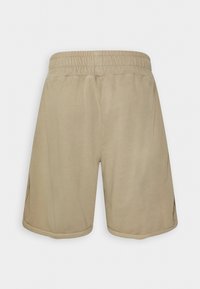 Pantalones cortos beige con una cintura elástica, hechos de una tela suave, presentan bolsillos laterales y un corte relajado. Las costuras están acabadas de manera prolija.
