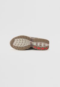 Shoe sole with a textured brown rubber base, featuring a segmented design and red circular accents for enhanced grip and flexibility.