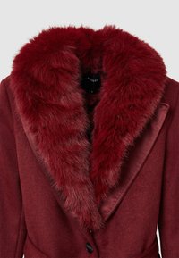 Bordeauxroter Mantel mit einem Kunstpelzkragen, verziert mit einem glatten Satinbesatz, elegantem Design und einem Einzelknopfverschluss. Weiche Textur und satte Farbe.