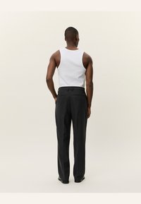 Zwarte heren pantalon met een rechte pijpdesign, gemaakt van een geweven stof. Inclusief achterzakken en een op maat gemaakte tailleband.