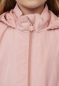 Jasnoróżowa kurtka z wysokim kołnierzem i marszczonym kapturem. Posiada zamek błyskawiczny z przodu z uchwytem w kształcie kwiatu oraz gładki, błyszczący materiał.
