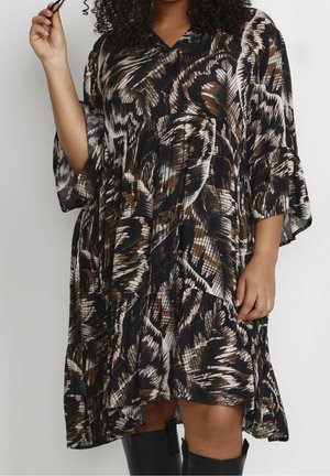 Musta, ruskea ja valkoinen kuvioitu mekko, jossa on V-pääntie, kolme neljänneksen pituista kellohihnaa ja kerroksittainen hameen muotoilu. Pehmeä, laskeutuva kangas.