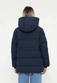 Námořnická puffer bunda s kapucí, s prošívanými částmi a zipovým uzávěrem. Hladký povrch a střední délka.