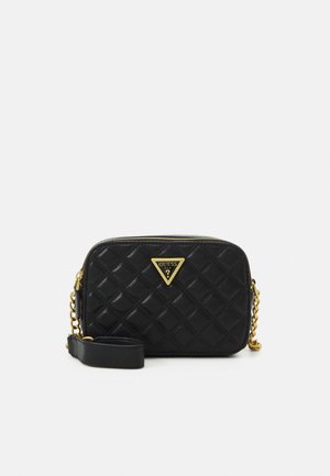 Black quilted crossbody bag with gold chain strap and triangular Guess logo plaque on front, zippered closure on top.