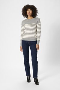 Pull rayé gris et crème avec des manches longues, un col rond et des poignets côtelés, associé à un jean droit bleu foncé et des bottines noires.
