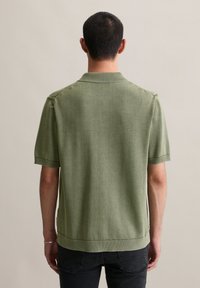 Koszulka polo z krótkim rękawem w stonowanym zielonym kolorze, z ribbowanym kołnierzykiem i mankietami, o teksturowanym wykończeniu i prostym dołem.