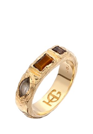Bague texturée en or avec trois pierres précieuses de formes différentes : marquise grise, ambre rectangulaire et carré brun foncé sertis sur l’anneau.