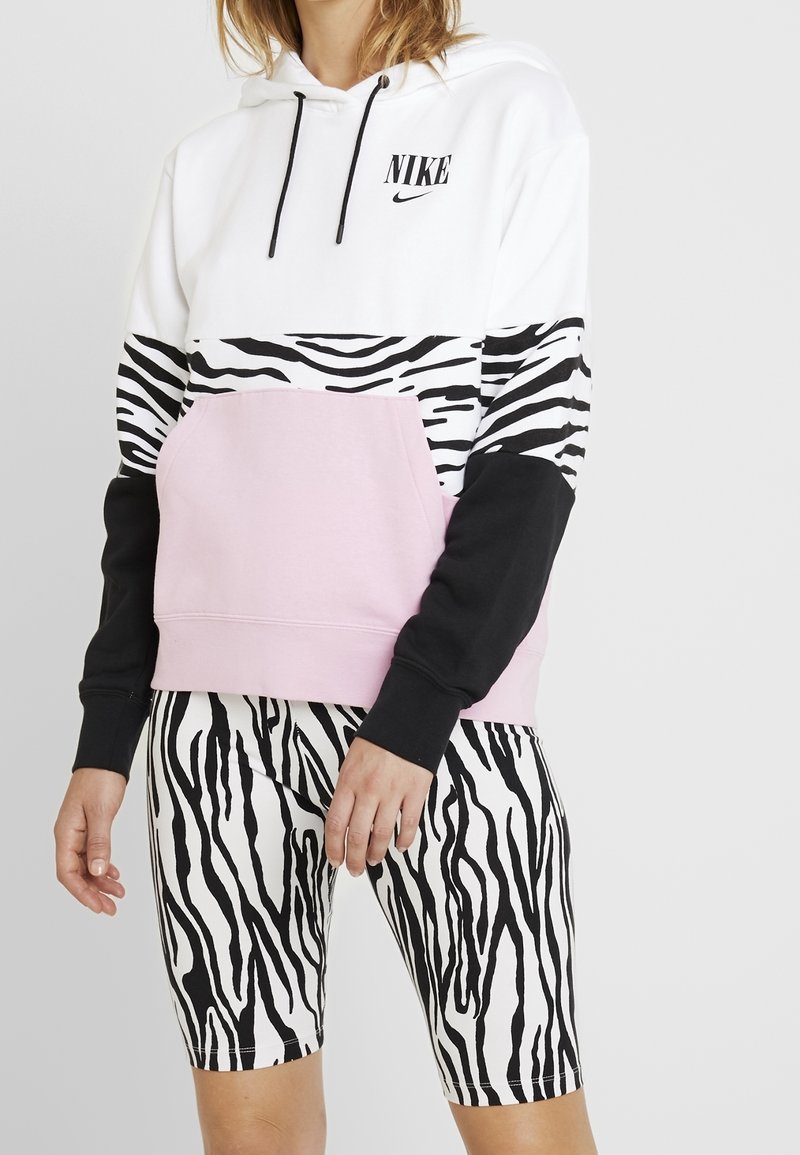 Hooded sweatshirt features black and white zebra stripes and a pink lower section; paired with matching zebra print shorts.