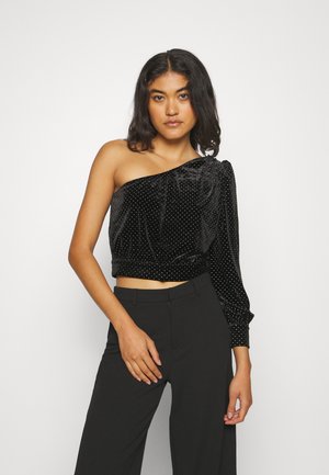 Černý sametový crop top s jedním ramenem, zdobený stříbrnými puntíky, s elastickým pasem a nabíraným dlouhým rukávem na pravé straně.
