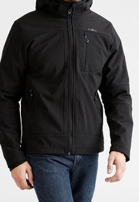 Veste softshell noire avec capuche, fermeture éclair à l'avant, poche poitrine et poches latérales. Caractéristiques : texture lisse et poignets réglables.