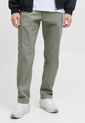 Pantalones de algodón verde oliva claro con un diseño de pierna recta y bolsillos traseros, combinados con zapatillas blancas. La tela es suave y casual.