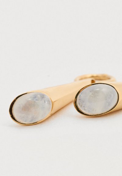 Σκουλαρίκια σε χρυσό χρώμα με επιμήκεις μορφές, διακοσμημένα με οβάλ διαφανείς λίθους, εξοπλισμένα με ασφαλές κούμπωμα για άνετη χρήση.