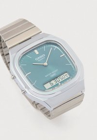 Sidabrinės spalvos skaitmeninis-analognis laikrodis su stačiakampiu korpusu, žydros spalvos ciferblatu, nerūdijančio plieno juosta, vandens atsparumu ir kvarco judėjimu.