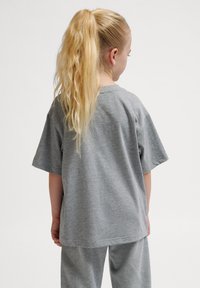 Grå bomulds t-shirt med korte ærmer, afslappet pasform, basic rund halsudskæring, set fra ryggen. Accepteret af matchende grå bukser.