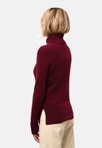 Maglione a collo alto color bordeaux realizzato in tessuto morbido, caratterizzato da una vestibilità comoda, spacchi laterali e collo e orlo a coste per una maggiore texture.