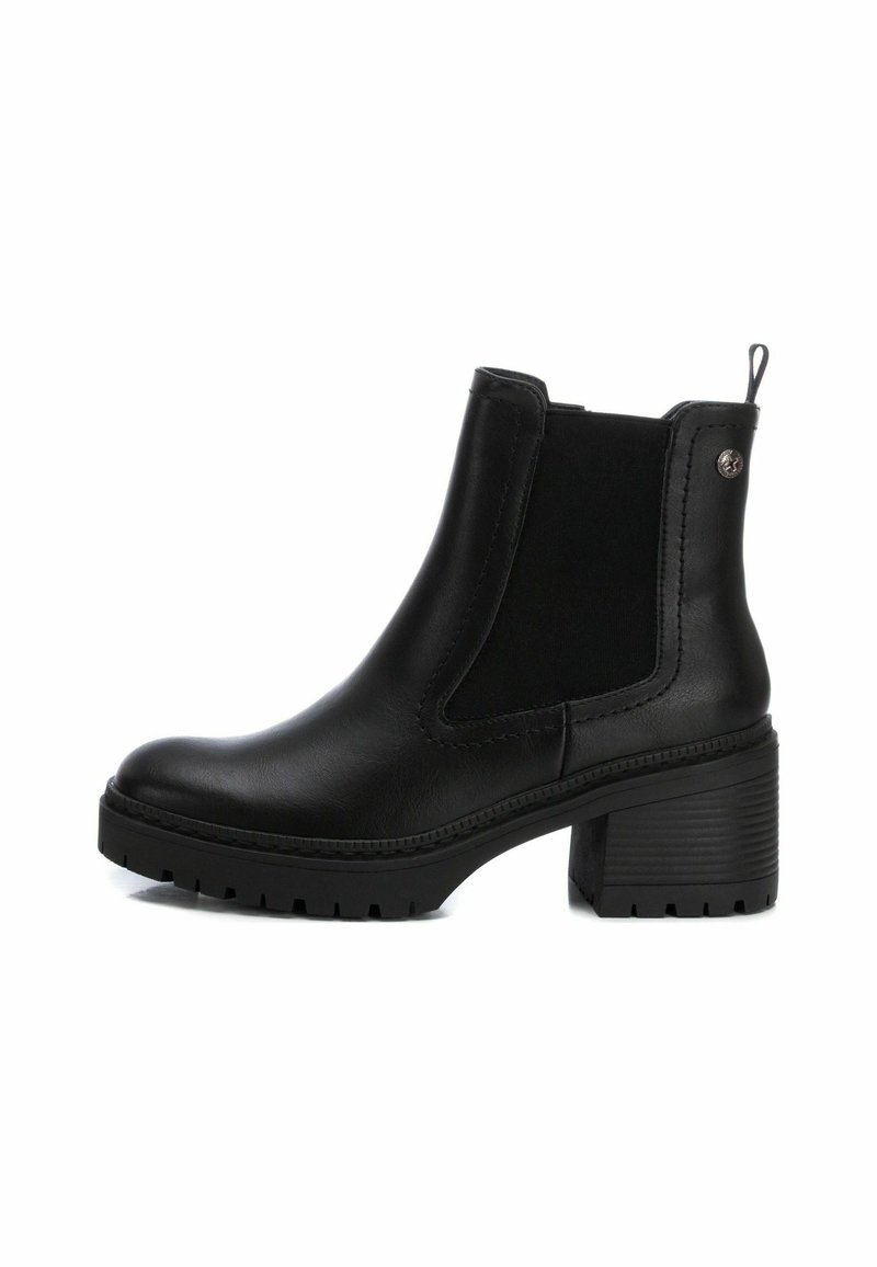 Botines negros de tobillo con un exterior de cuero liso, paneles laterales elásticos, un tirador y un tacón grueso con una suela texturizada.