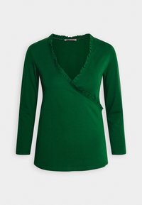 Grünes langärmeliges Wickeloberteil mit V-Ausschnitt und Rüschensaum entlang des Ausschnitts, aus einem weichen, dehnbaren Stoff gefertigt.