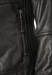 Schwarze Lederjacke mit einer Reißverschlusstasche, gestepptem Muster an den Ärmeln und Stitching-Details an den Nähten.