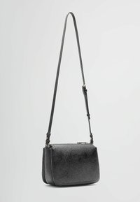 Sac à épaule noir en cuir texturé, doté d'une sangle mince, de forme rectangulaire et d'une fermeture éclair avec des accents matériels minimaux.