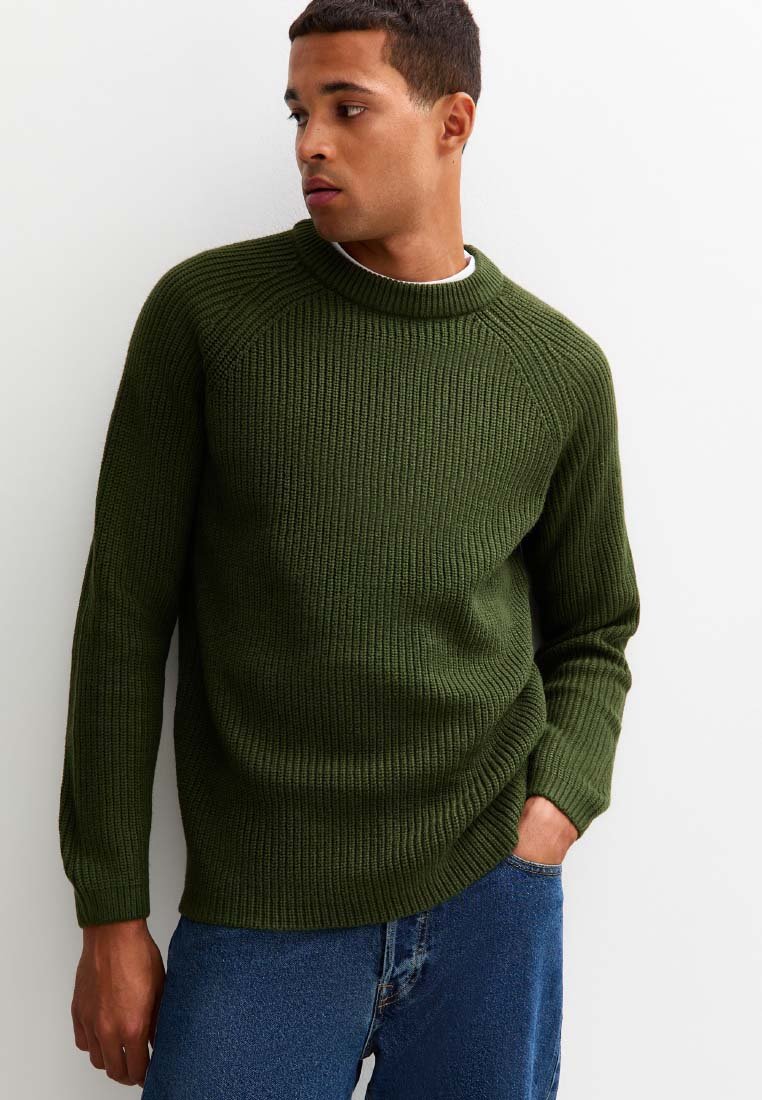 Mörkgrön ribbad tröja med hög krage, långa ärmar och figurnära passform. Texturen är stickad och skapar ett upphöjt mönster.