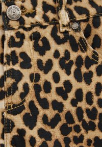 Tkanina s leopard uzorkom koja ima bež pozadinu s crnim mrljama. Uključuje metalne dijelove s ugraviranim nazivom "Blue Ridge" na dugmetu.