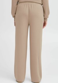 Afslappede beige sweatpants med elastisk talje, blød tekstur og brede ben, designet til komfort og let bevægelse.