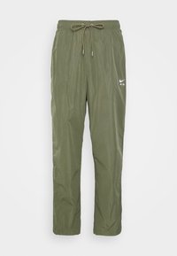 Olivově zelené, lehké nylonové joggingové kalhoty s elastickým pasem, nastavitelnou šňůrkou a malým bílým logem Nike Air na boku.