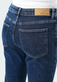 Tmavě modré džíny z denimu s koženou nášivkou s nápisem "NOISY MAY" na pase, standardní zadní kapsy a úzkým střihem.