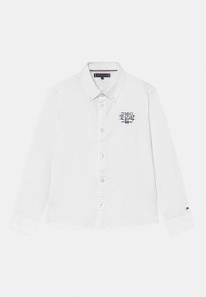 Biała koszula z długim rękawem zapinana na guziki, kołnierz z guzikami, haftowane logo "Tommy Hilfiger New York City" na piersi oraz logo flagi na lewym mankiecie.