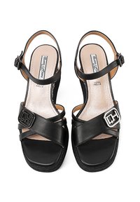 Sandali in pelle nera con fasce incrociate, dettagli in fibbia, soletta imbottita e suola testurizzata. Design aperto per il tallone e le dita dei piedi.