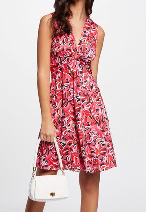 Mouwloze jurk met bloemenpatroon in levendige rood- en roze tinten, met een gespen taille, gecombineerd met een witte gewatteerde handtas met een gevlochten band.