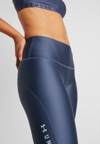 Laivastonsiniset kompressiotrikoot, joissa on sileä pinta, korkea vyötärönauha ja litteät saumat. Varustettu nilkassa olevalla logolla ja vartalonmyötäisellä leikkauksella.