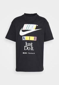 T-shirt noir Nike avec le texte multicolore "NIKE" et "AIR", logo swoosh blanc, slogan "Just Do It." et détails de la marque Beaverton, OR.