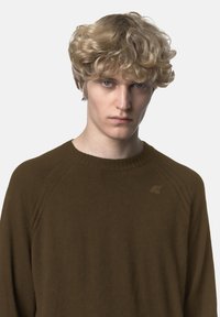 Maglione marrone in maglia con scollo a girocollo a coste, spalle scese e un piccolo logo sul petto. Texture morbida e vestibilità comoda.