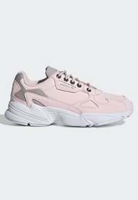 Zapatillas deportivas de color rosa claro con una parte superior texturizada, detalles de malla y una suela blanca. Cuenta con un collar acolchado y cordones grises para mayor soporte.